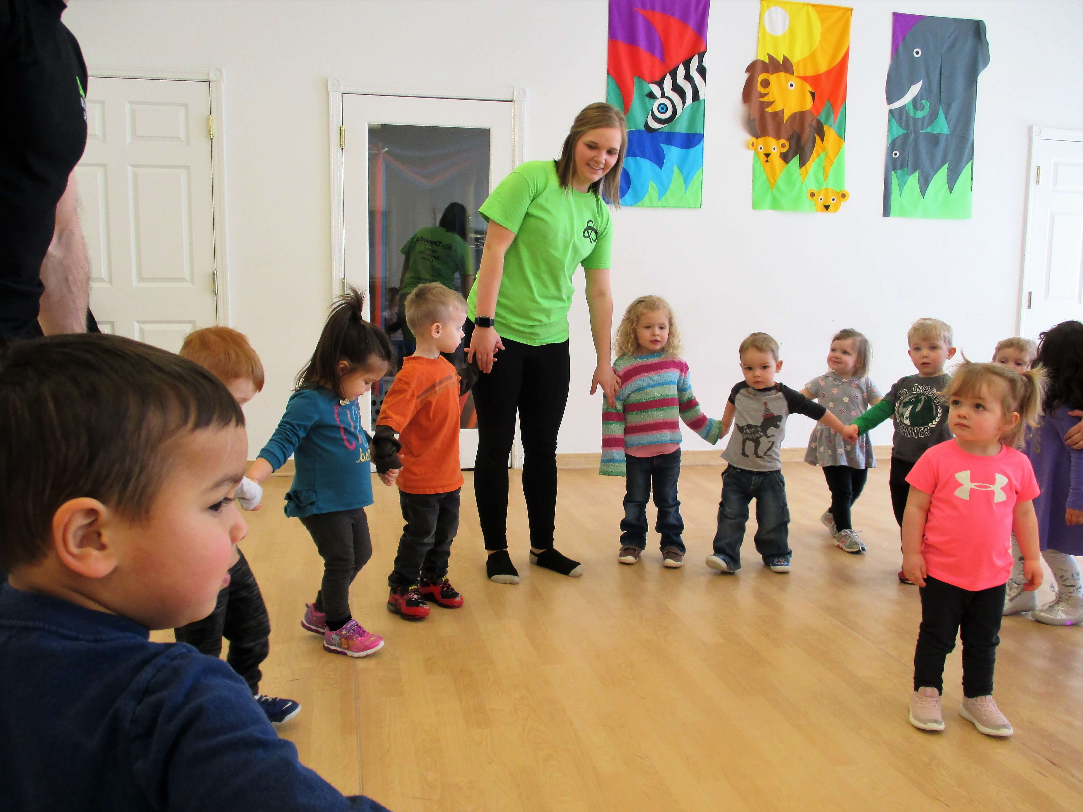 Preschool teacher holding hands with children in a circle